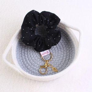 Detail of black rhinestone velvet scrunchie with golden leaf pendant in woven basket
