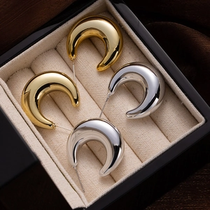 Detailed view of polished gold and silver C-shaped hoop earrings inside a jewelry box