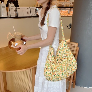 Close-up of a floral canvas tote bag featuring yellow kumquat patterns and wide shoulder straps