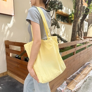 Close-up of vibrant yellow nylon tote bag featuring green Bonjour printed lettering