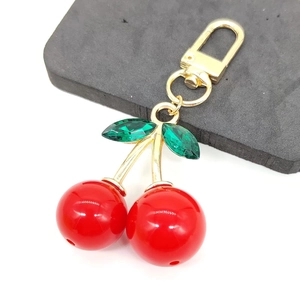 Detail of red cherry keychain with green crystal leaves and gold lobster clasp