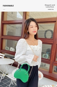 Detail of trendy neon green PVC heart shaped jelly bag with elegant gold chain strap