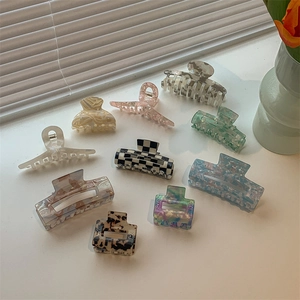 Detail shot of acetate hair claws in checkered, marble, and amber patterns on a white surface