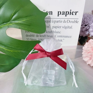 Detailed view of white organza drawstring gift bag with elegant red ribbon bow