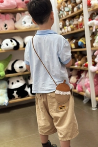 Close-up of an acorn-shaped leather crossbody bag for kids with white lace trim details