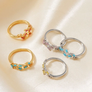 Artistic collection of gold and silver leaf rings with colorful gemstones on silk fabric