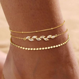 Detailed view of triple-layered gold ankle bracelets with zircon and beads on ankle