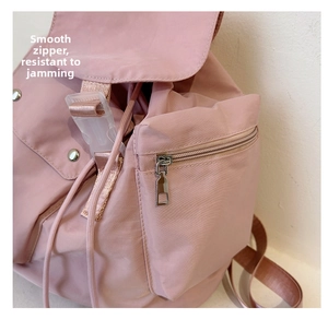 Detail of smooth metal zipper and side pocket on a pink water-resistant nylon backpack