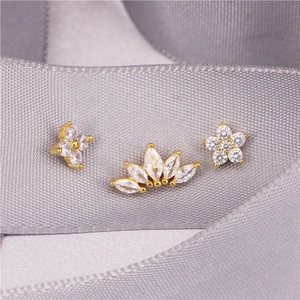 Macro shot of gold ear cuff set featuring clover and crown designs with zircon stones