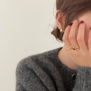 Close-up of elegant gold V-shaped ring and twisted band on a model with red nails