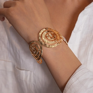 Détail d'un bracelet manchette spirale doré martelé porté au poignet d'une femme