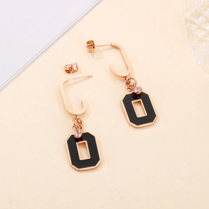 Detail of rose gold rectangular earrings with black enamel inlay and zircon accent
