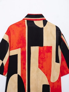 Detail of short sleeve shirt showing abstract geometric print in red, black and beige