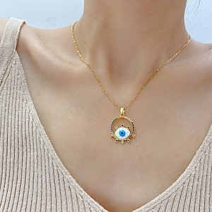 Close-up of golden necklace featuring a blue evil eye pendant with colorful zircons