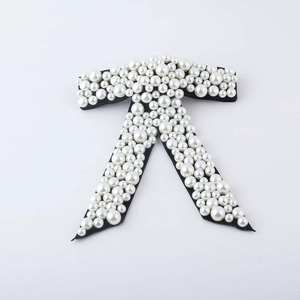 Macro detail of luxury black bow hair clip with white pearls and sparkling rhinestone inlay
