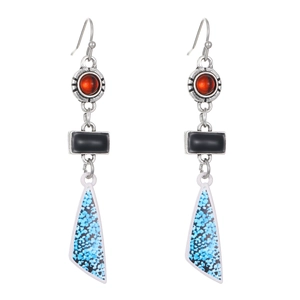 Macro detail of bohemian geometric earrings with blue floral textures and red beads