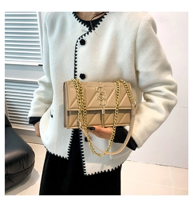 Detail of beige quilted shoulder bag with gold chain strap and decorative tassel