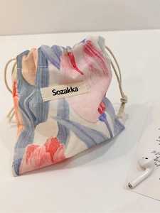 Floral drawstring organizer bag with tulip patterns and woven brand label on white surface