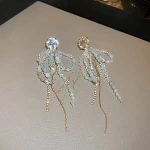 Macro detail of bow-knot tassel earrings with blue crystals and shimmering long chains