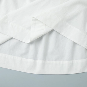 Gros plan détaillé montrant les coutures fines et la texture du tissu en coton blanc du vêtement