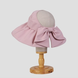 Visiera parasole rosa a tesa larga con fiocco decorativo su testa di manichino