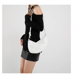 Close-up of minimalist white leather crescent bag featuring a unique knotted shoulder strap