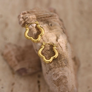 Detailed macro view of golden hammered wavy earrings on a textured natural rock