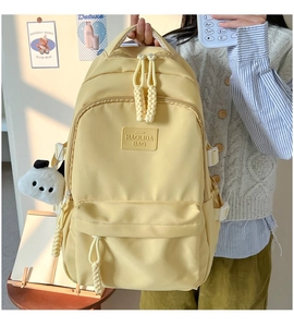 Close-up of cream nylon backpack featuring brand patch and a cute panda plush charm
