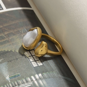 Detailed view of an open gold stainless steel ring with a pearl on an open magazine