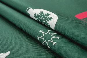 Close-up of green festive tablecloth featuring intricate weave and Christmas patterns