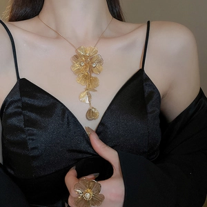Detail of gold floral necklace and ring set with sparkling crystals on black velvet