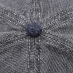 Macro view of stitched seams and top button on washed grey cotton baseball cap