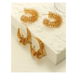 Détail de boucles d'oreilles dorées forme C avec design de fil tordu irrégulier