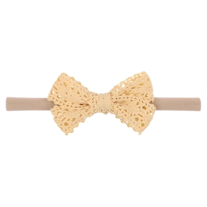 Close-up of soft nylon baby headband with delicate cream lace bow on white background
