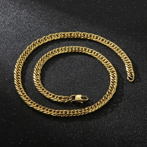 Detail of gold Cuban chain link necklace with lobster clasp closure on black surface