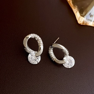 Macro view of silver tone stud earrings with sparkling cubic zirconia on brown leather