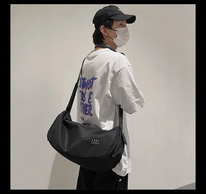 Neutral black nylon sports bag shown in a stylish crossbody carry on model