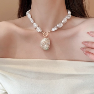 Detail of baroque pearl necklace with gold toggle clasp and large spiral shell pendant