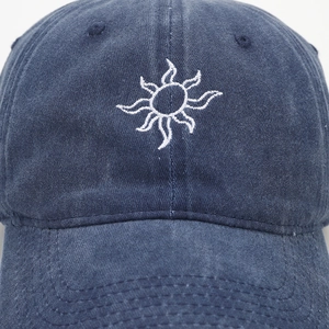 Detailed close-up of sun embroidery on a vintage navy blue denim baseball cap