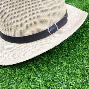 Detail of beige woven straw hat featuring dark brown PU leather band and silver metal buckle