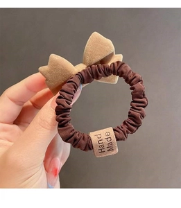 Close-up of handmade bow hair scrunchie featuring velvet ribbon and satin texture