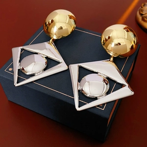 Detailed view of large gold and silver geometric diamond drop earrings on a jewelry box