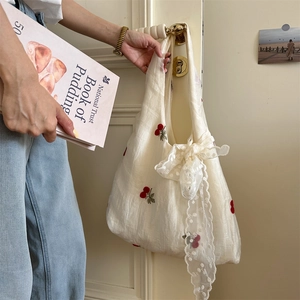 Detail of cherry embroidered tote bag with delicate lace bow and soft fabric texture