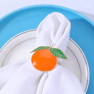 Detail of orange fruit napkin ring with green leaf on a white and blue ceramic plate