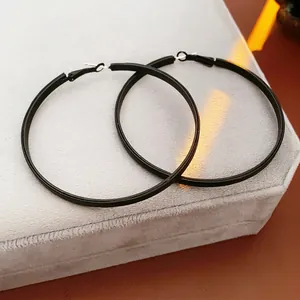 Boucles d'oreilles créoles rondes en cuir noir mat pour femmes sur présentoir en velours