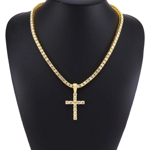 Gold tennis necklace with sparkling iced-out cross pendant displayed on a black bust