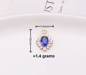 Macro detail of gold-plated sunburst charm with blue gemstone and dimensions 13x18mm
