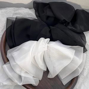 Detail of oversized black and white chiffon bow clips on a wooden tray background