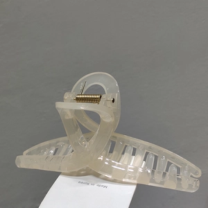 Detail of elegant beige jelly hair claw clip with golden metal spring and Korean design