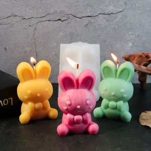 Easter rabbit silicone mold with three colorful bow-tie candles on a rustic background